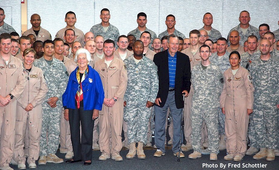 Group photo of military personnel and civilians standing together indoors.